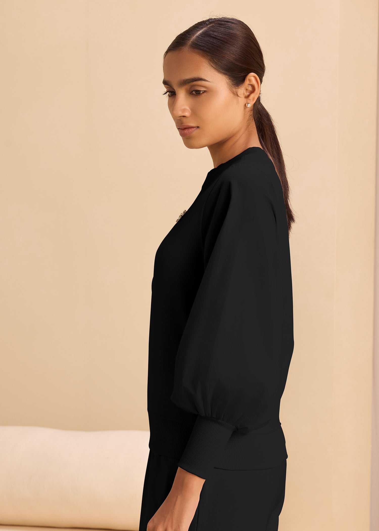 A woman in a black sweatshirt, highlighting a relaxed and trendy outfit choice.